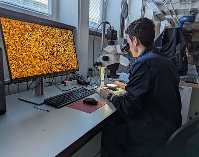 Človek opazuje skozi mikroskop.